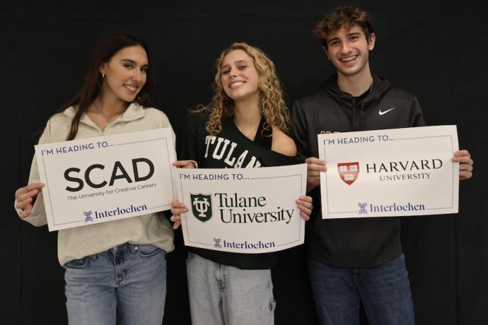 Three smiling students hold up their college decision signs.