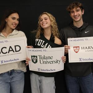 Three smiling students hold up their college decision signs.
